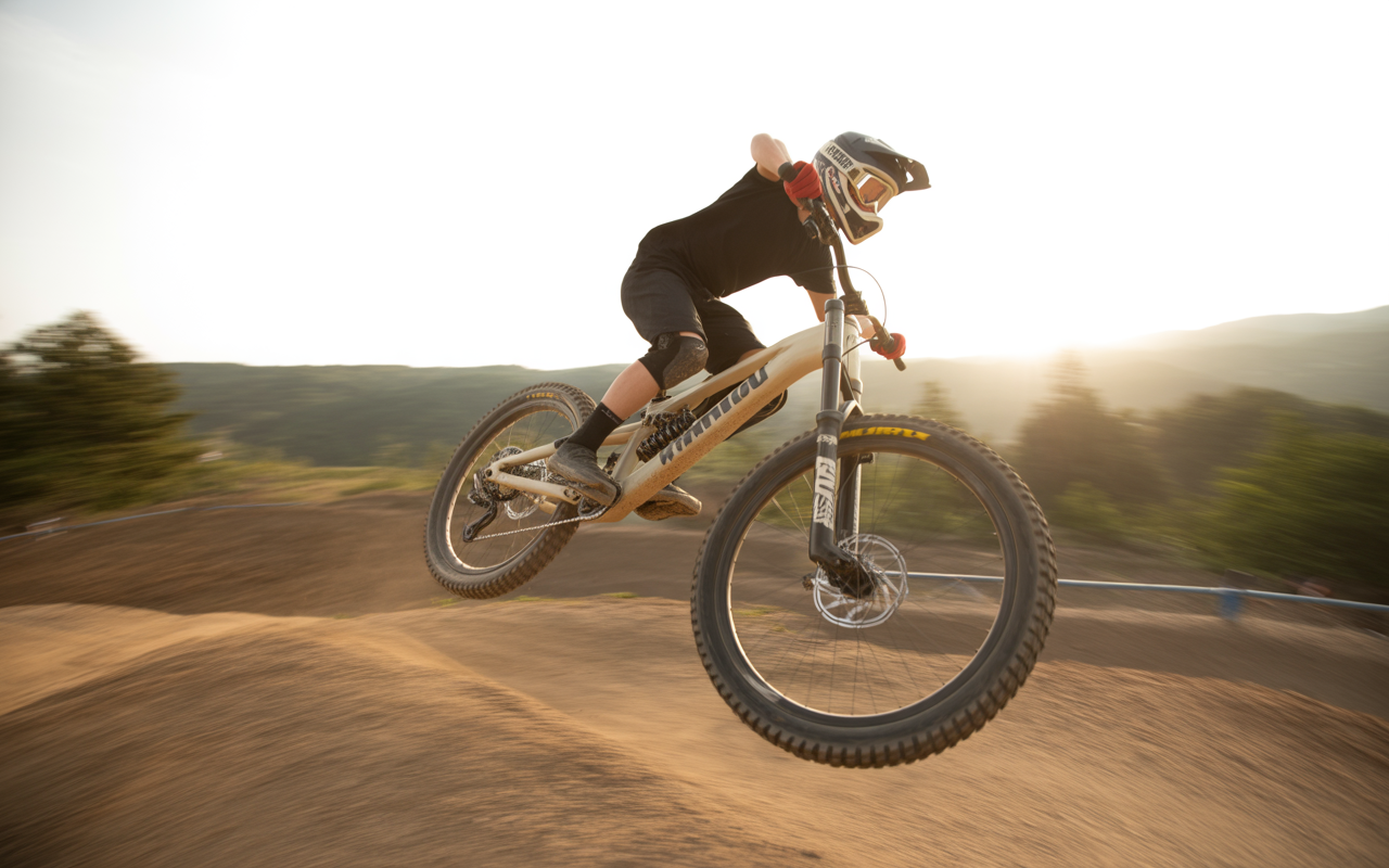 Un jeune cycliste en plein saut sur une piste de vélo tout terrain au coucher du soleil, montrant vitesse et agilité.