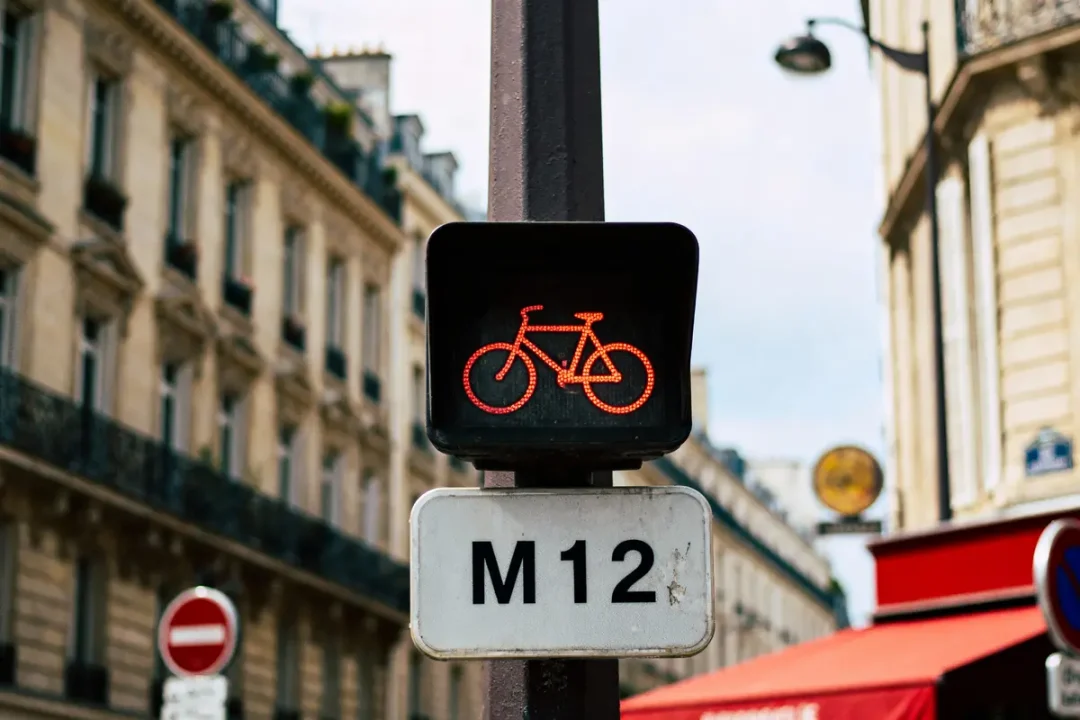Feu rouge pour vélos avec panneau M12 dans une rue urbaine parisienne.