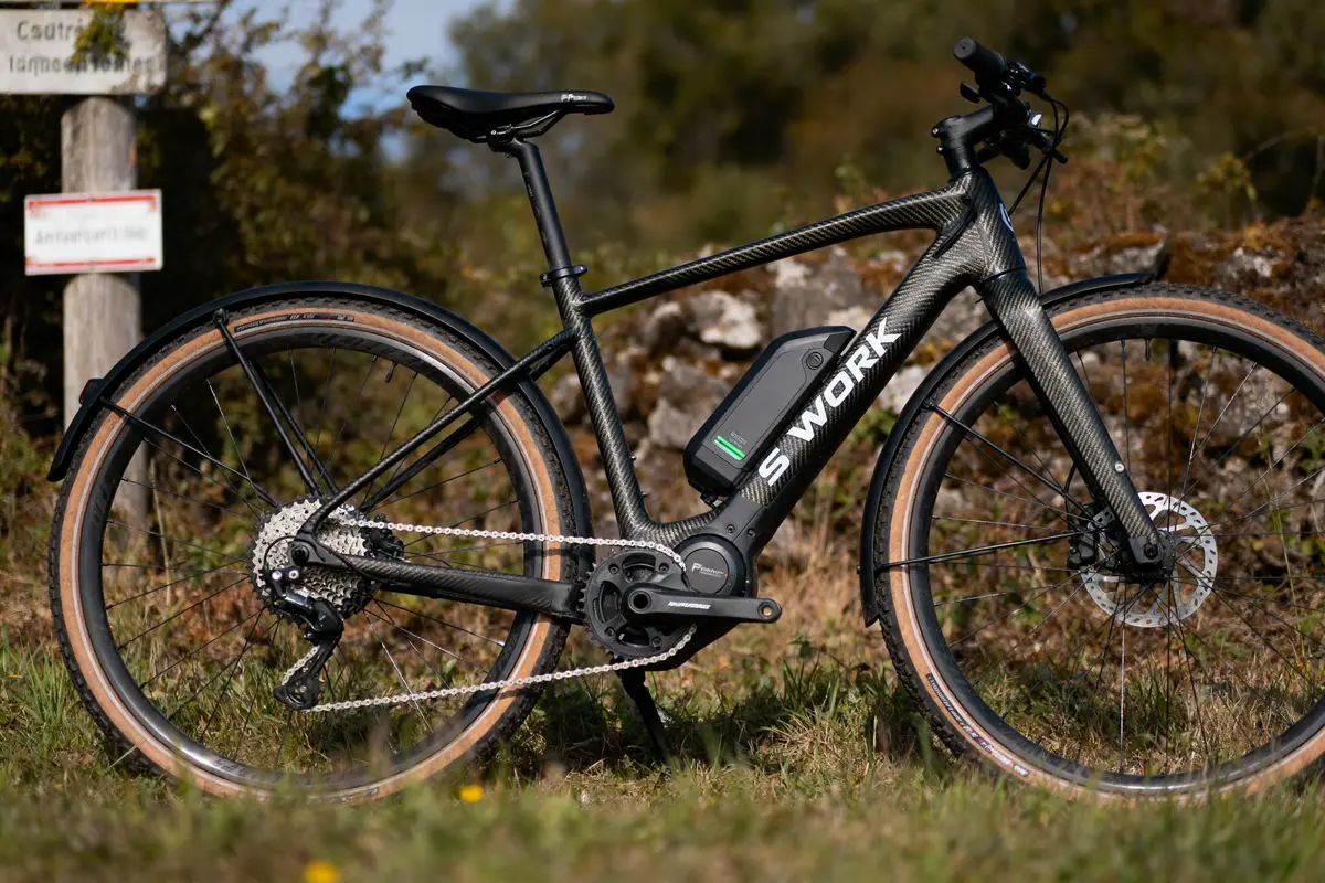 Vélo électrique S-Works noir stationné sur un chemin, vue latérale, paysage naturel en arrière-plan.