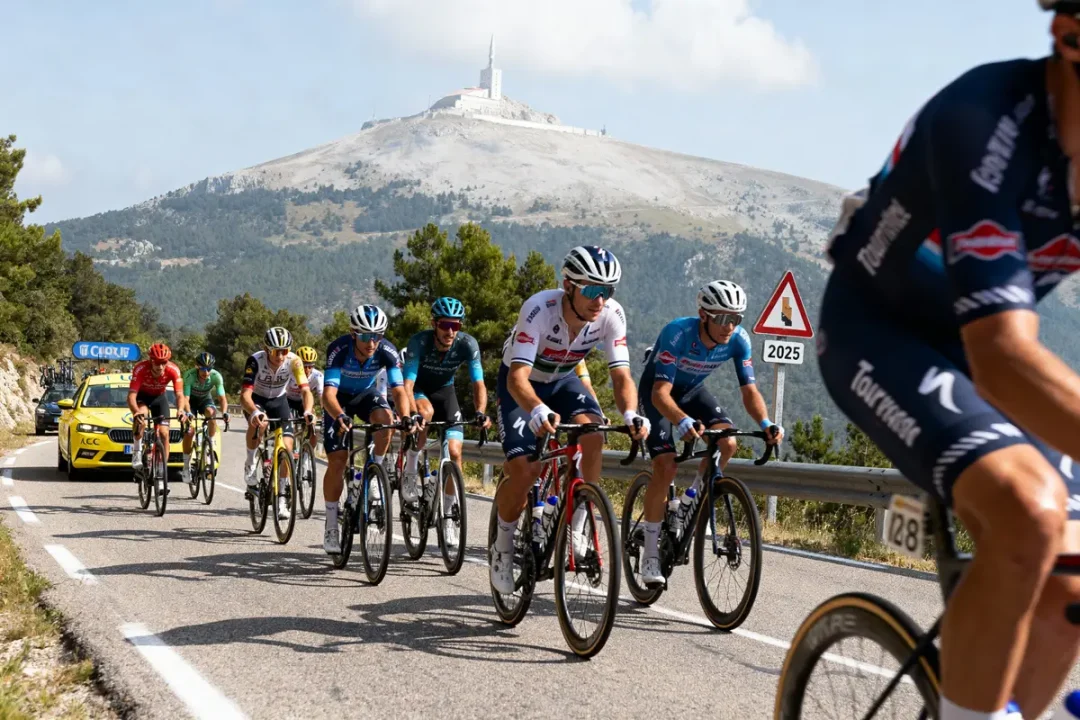 Cyclistes sur route montagneuse, Mont Ventoux en arrière-plan, suivi par voiture. Panneau avertissement visible.