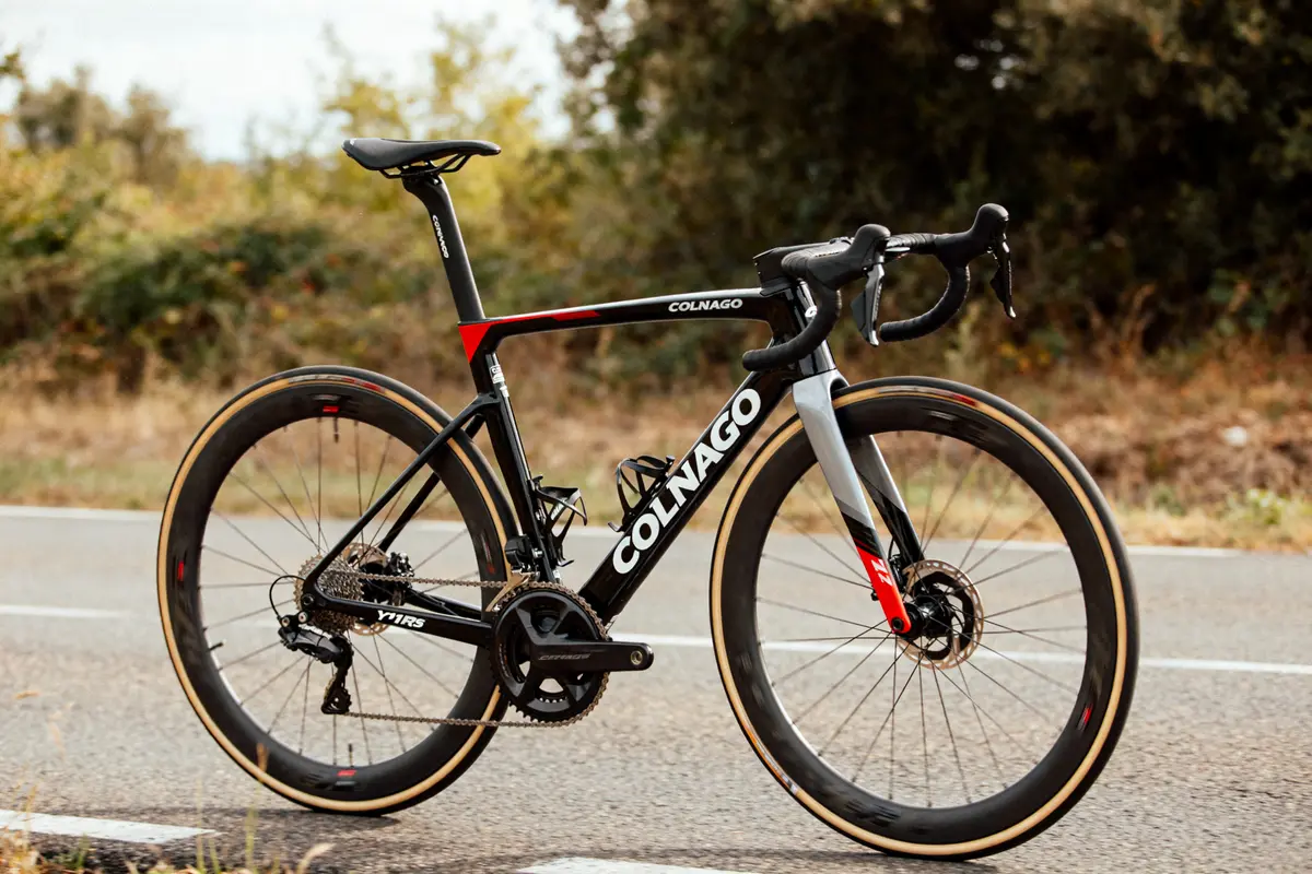 Vélo route Colnago Y1RS noir et rouge stationné sur une route arbres en arrière-plan