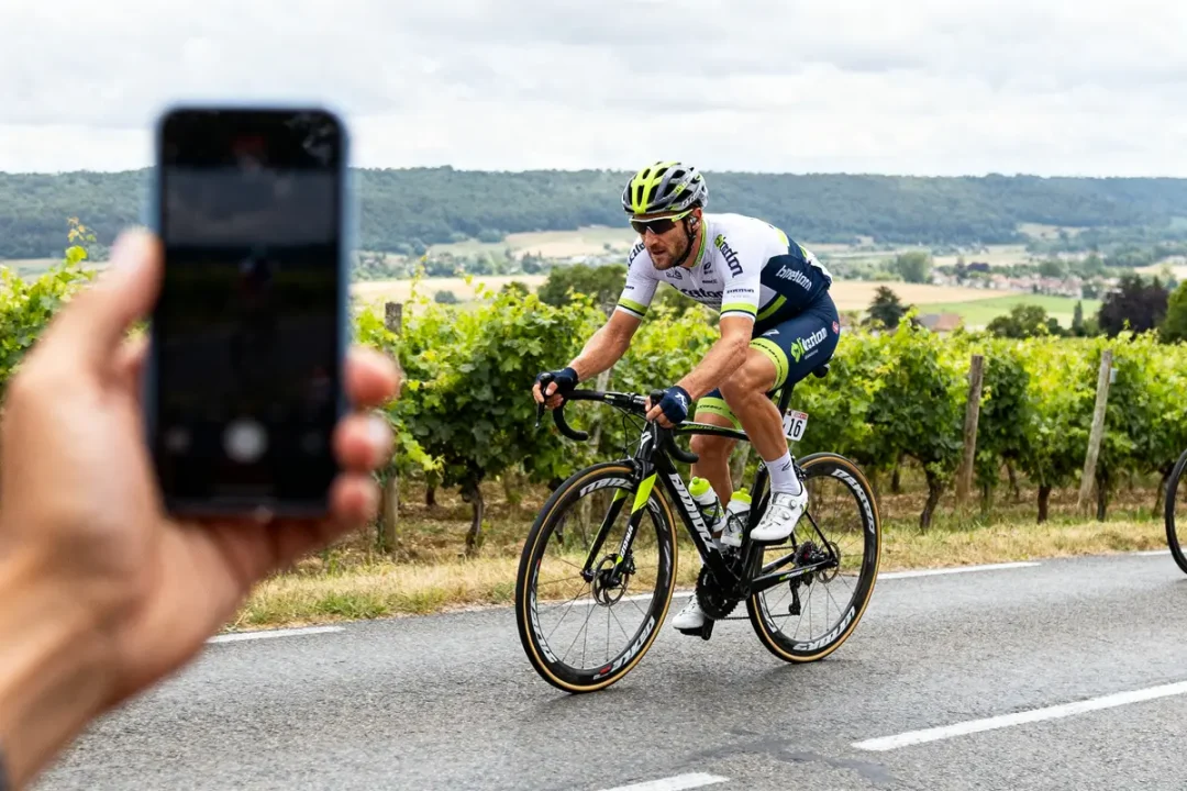 Cycliste sur route près de vignobles lors d'une course, évoquant Fabian Cancellara