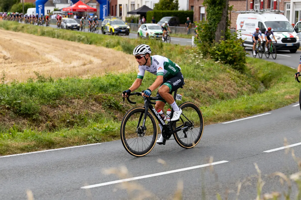 Cycliste en tenue Heistse sur une route de campagne pendant une course cycliste.