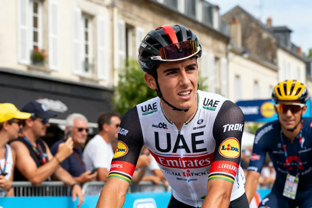 Cycliste Juan Ayuso en tenue UAE Team Emirates durant une course avec des spectateurs.