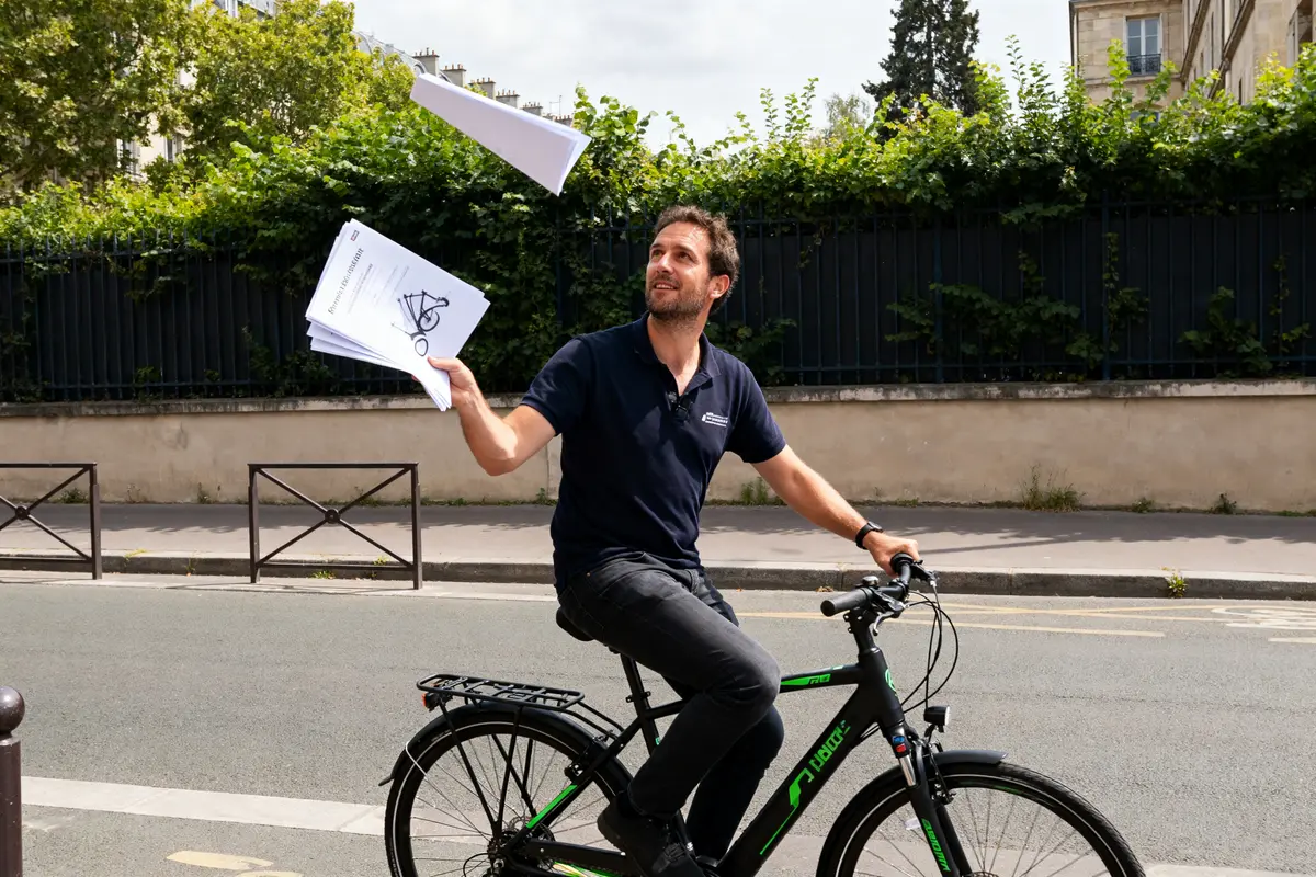 L'homme sur vélo lance des feuilles en l'air, représentant The Bicycle Entrepreneur dynamique.