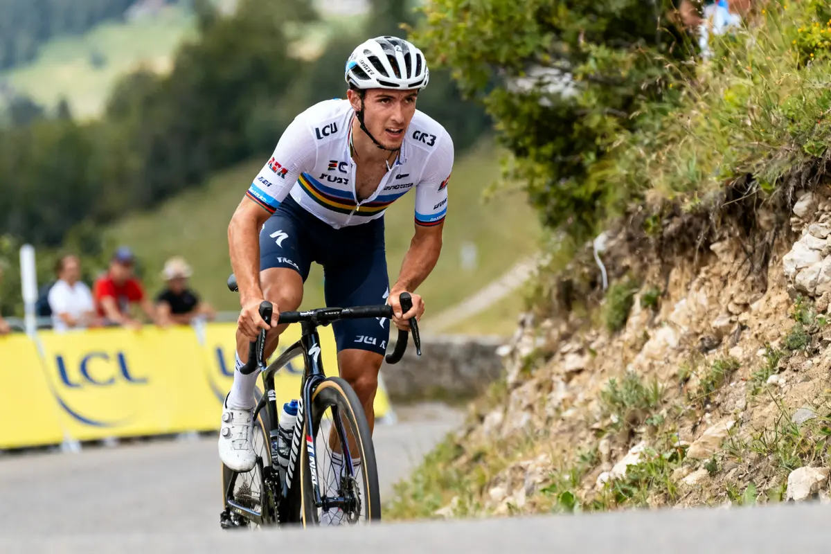 Cycliste en montée lors d'une compétition, Felix Gall portant un maillot blanc racing.