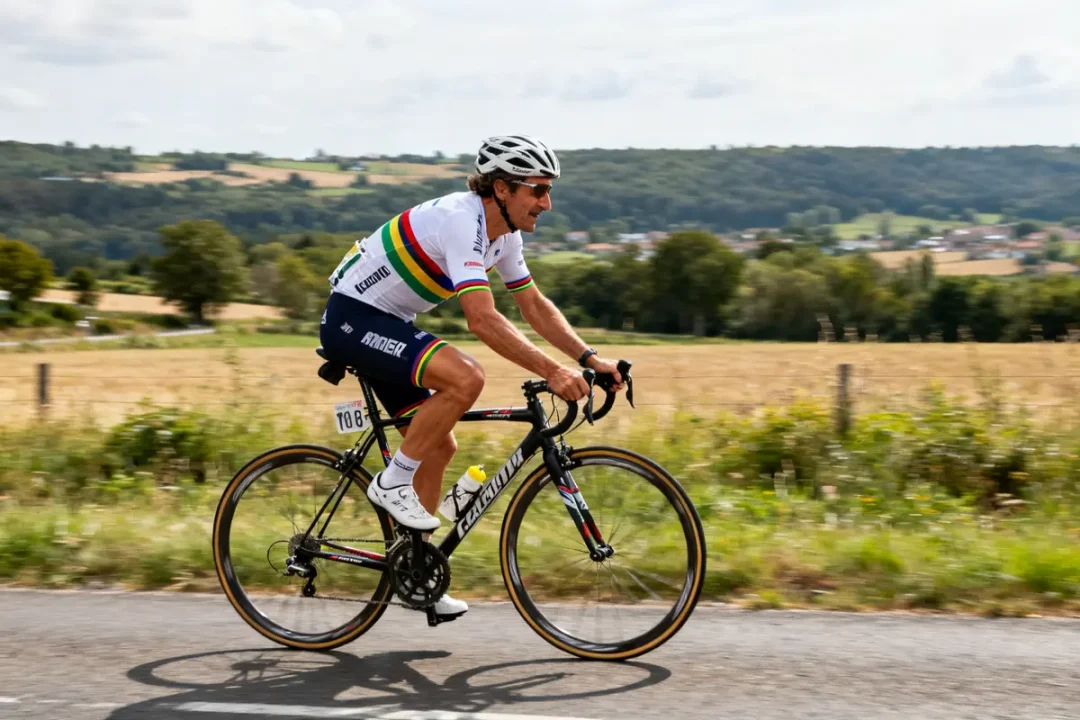 Cycliste sur route, maillot arc-en-ciel, paysage rural, Stephen Roche en action vélo.