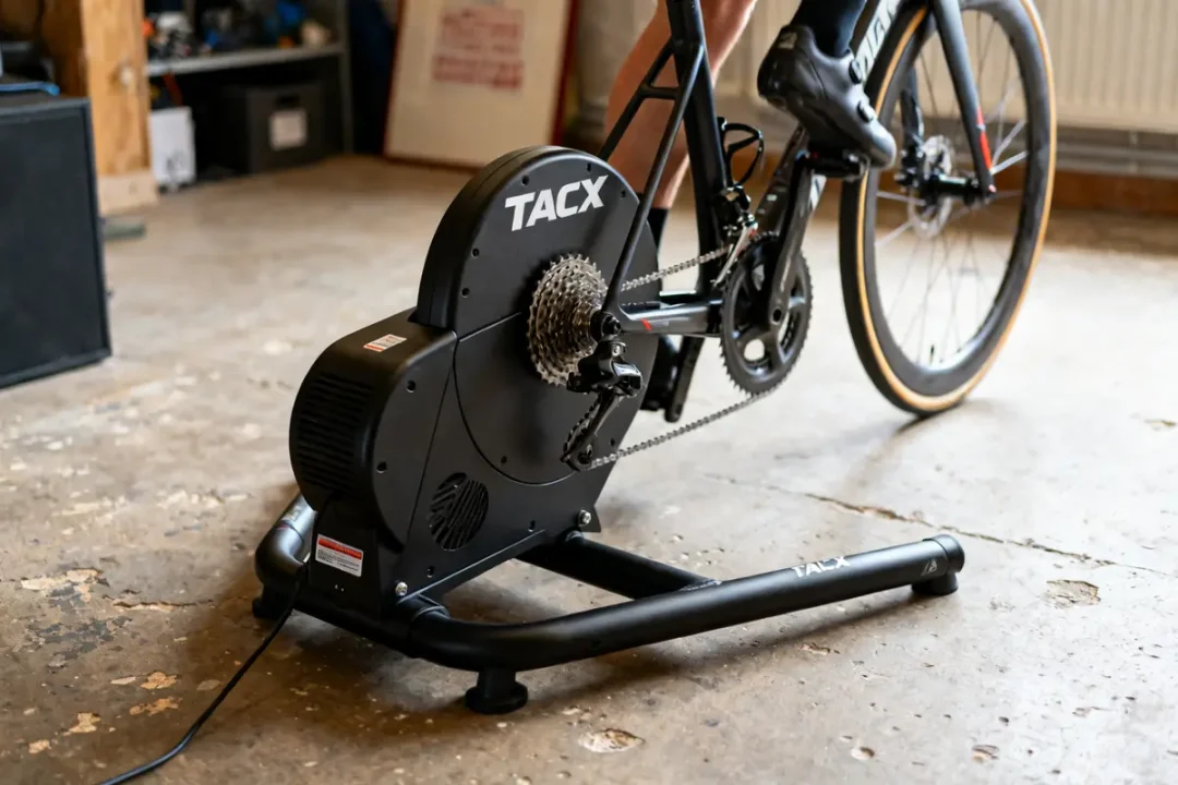 Homme utilisant un home trainer Tacx Flux S avec vélo dans un garage équipé