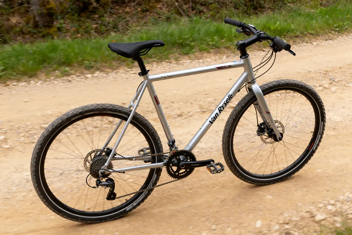 Vélo gravel Van Rysel roulant sur chemin de terre battue en pleine nature verdoyante